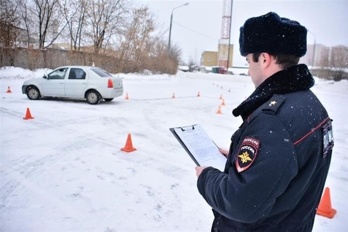 Автодром, покрытый снегом, где находится автомобиль в сопровождении инспектора.